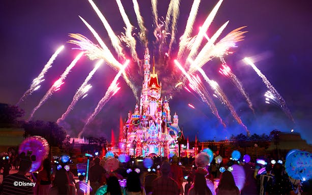 People watching fireworks at night by the Disneyland Castle, Hong Kong Disneyland