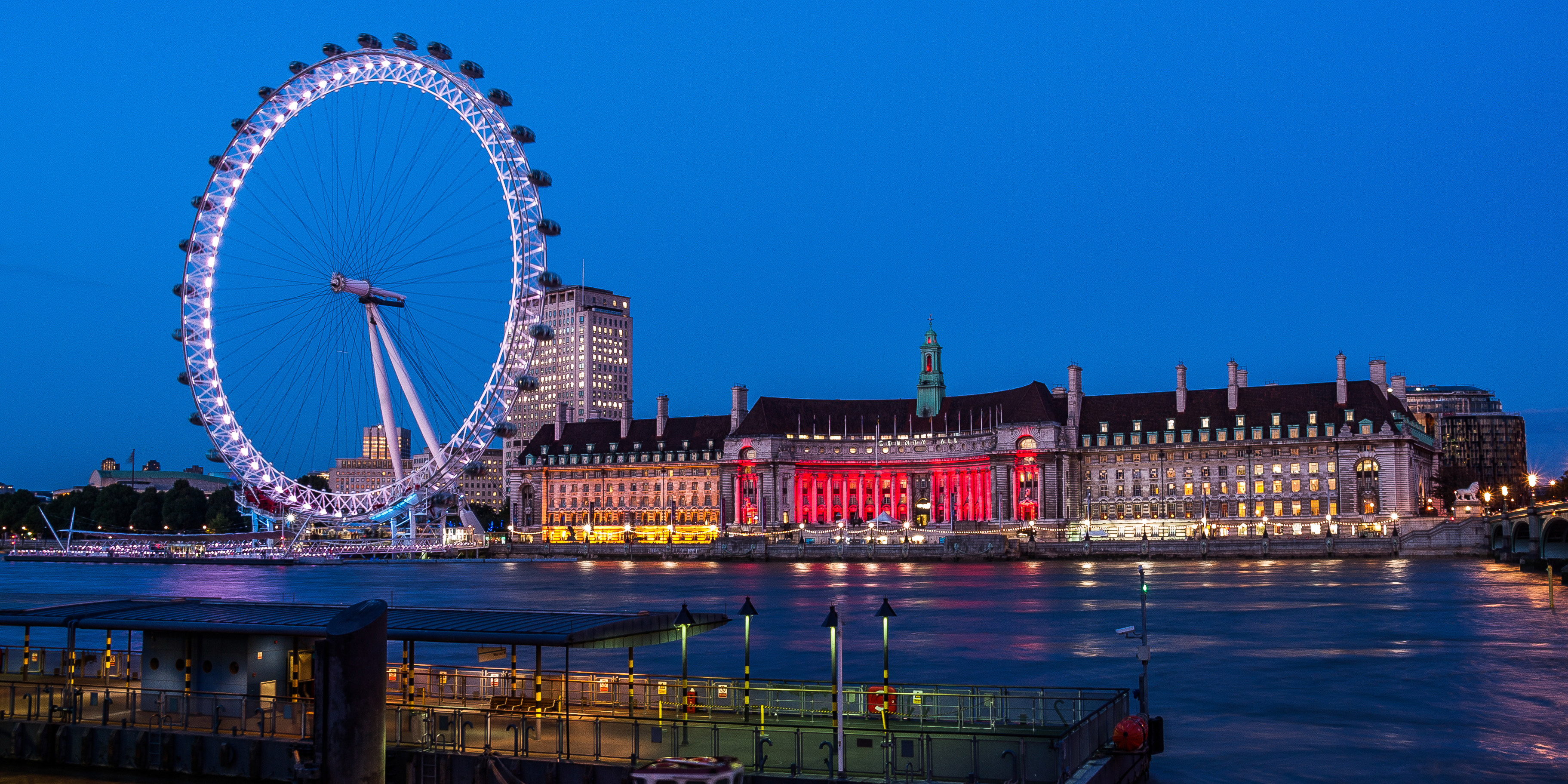 London Eye and County Hall illuminated at night from the South Bank.