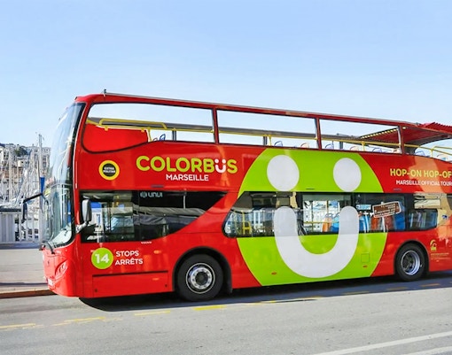 Touristes profitant de la visite de Marseille en bus touristique Hop-On Hop-Off avec une vue panoramique de l'architecture historique de la ville.