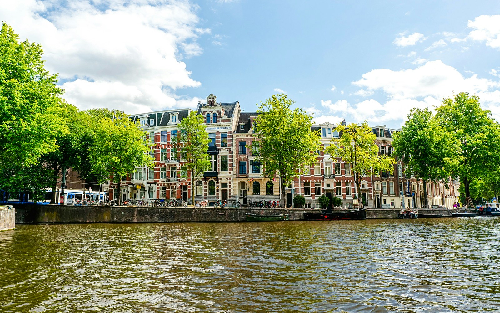Canal view of historic buildings along Leidsekade in Amsterdam.