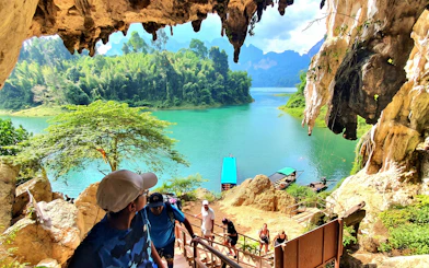 Tourists hiking from Diamond Cave with view of Cheow Lan Lake, Krabi boat tour in lush jungle setting.