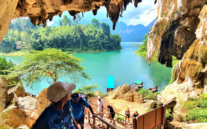 Tourists hiking from Diamond Cave with view of Cheow Lan Lake, Krabi boat tour in lush jungle setting.