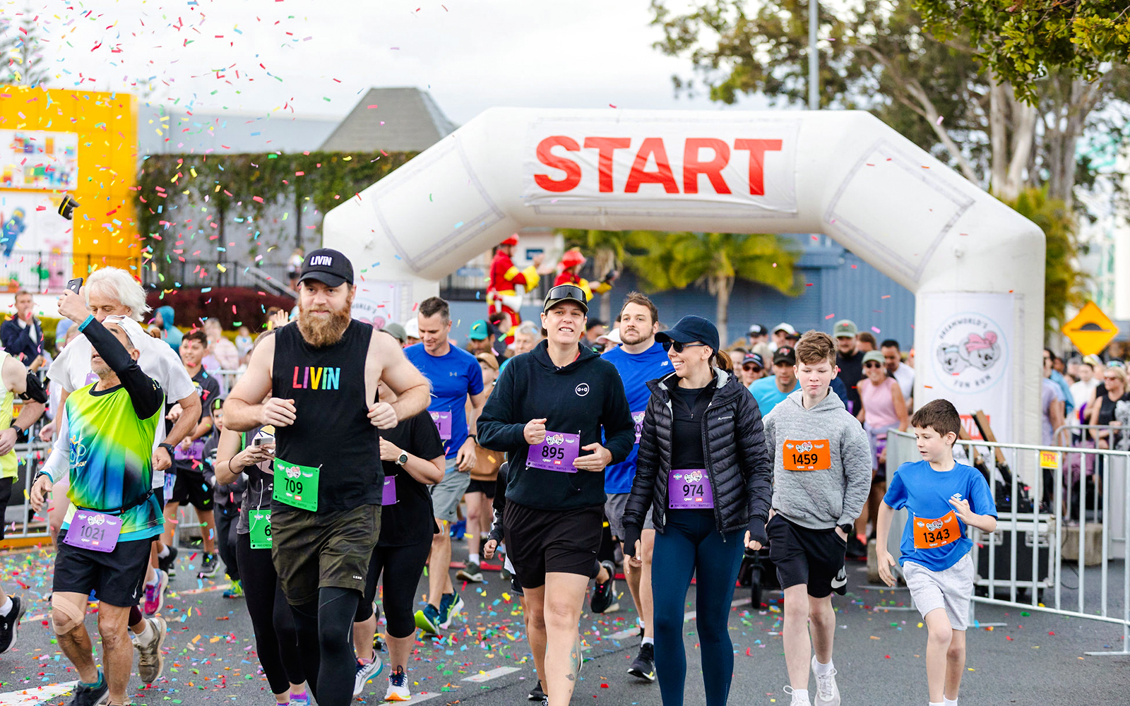Participants in a fun run at Dreamworld, Gold Coast, wearing colorful outfits and running past theme park attractions.