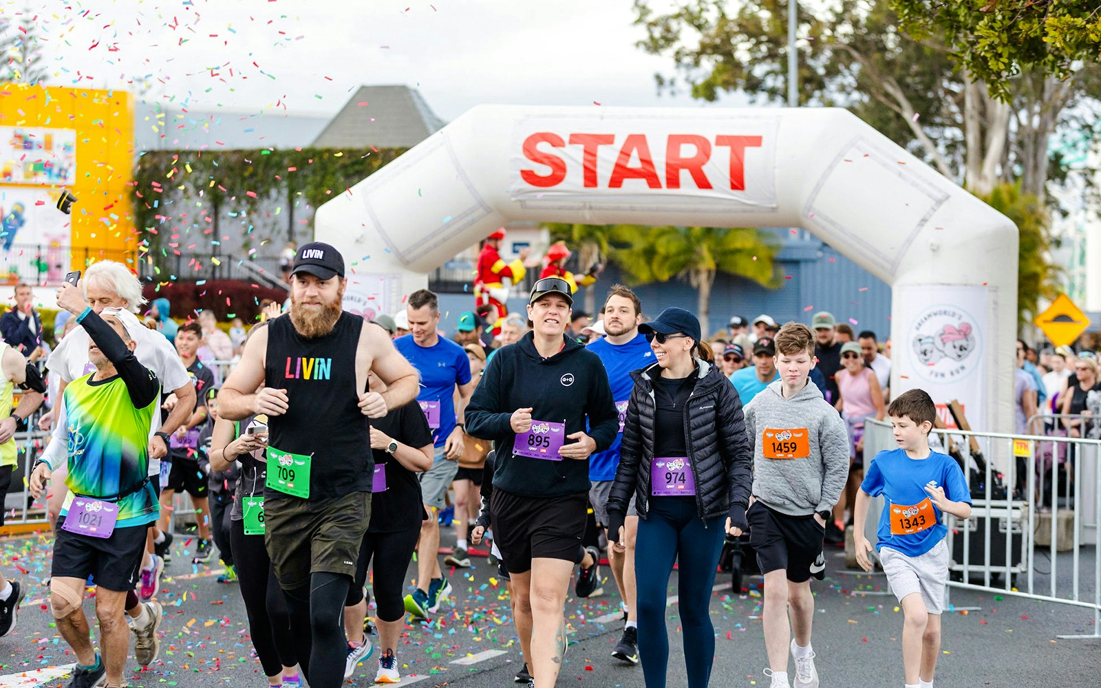 Participants in a fun run at Dreamworld, Gold Coast, wearing colorful outfits and running past theme park attractions.