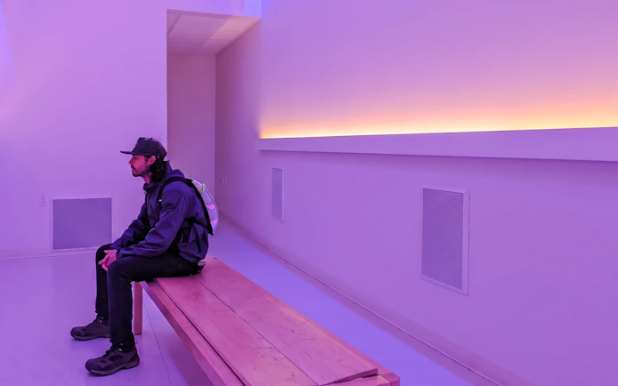 Person sitting on a bench in a purple-lit room during Fairbanks Heritage Tour.