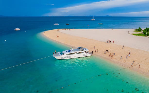 Seanery catamaran docked at Bamboo Island with tourists on the sandy beach.