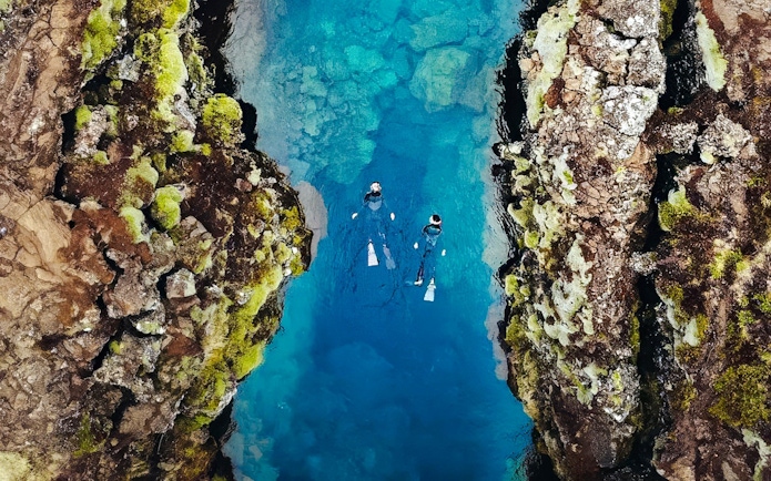 Snorkelers exploring the clear waters between tectonic plates in Silfra, Iceland.