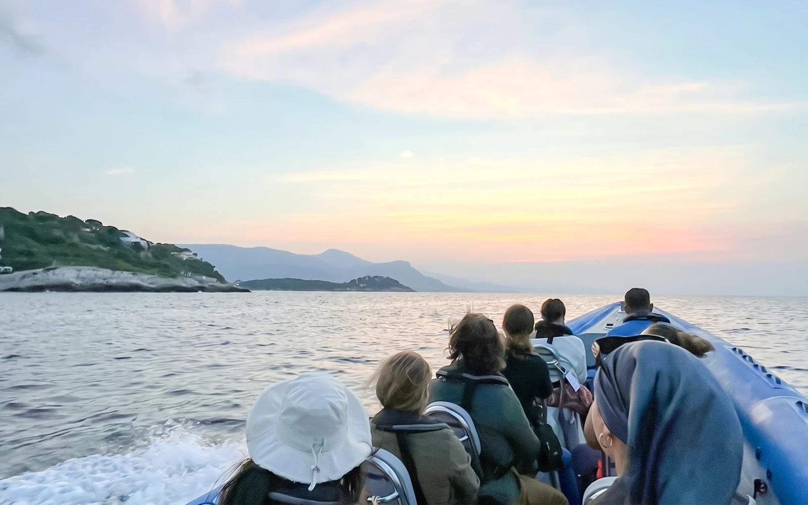 Boat tour group heading towards Villefranche and Mala Cove at sunset.