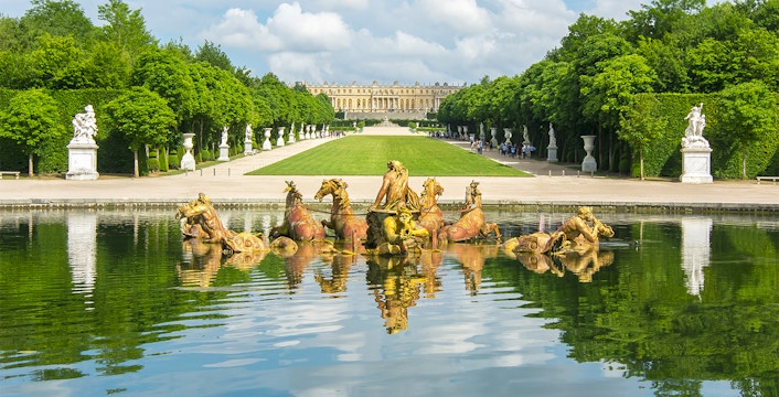 Apollo fountain in Versailles Palace Gardens with palace in background.