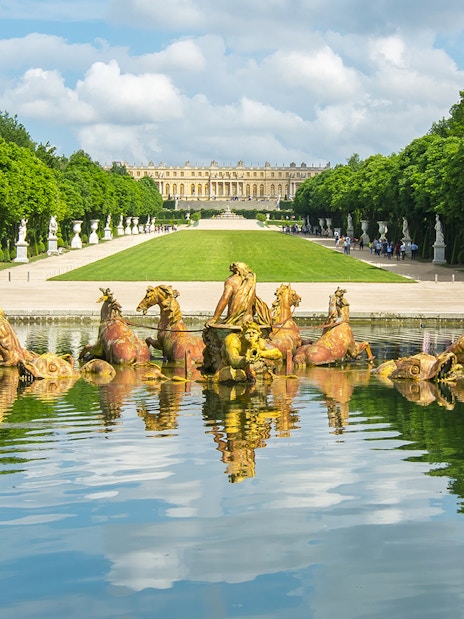 Apollo fountain in Versailles Palace Gardens with palace in background.