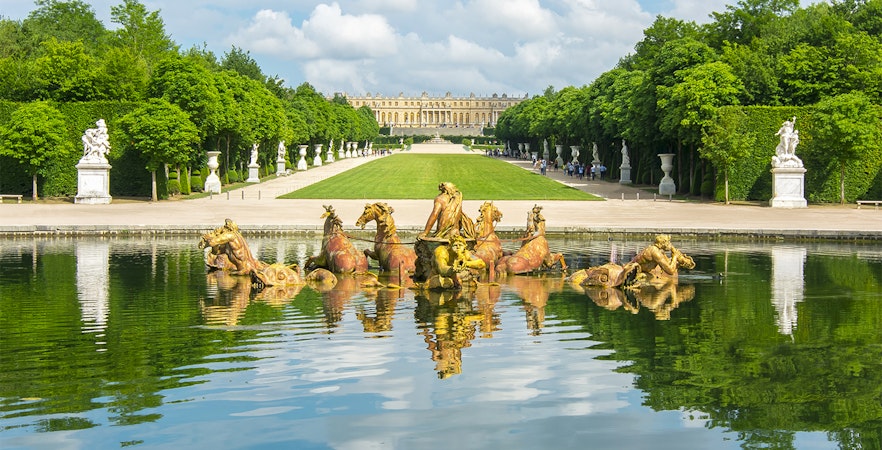 Apollo fountain in Versailles Palace Gardens with palace in background.