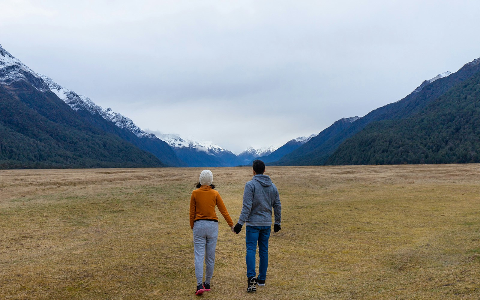 Couple walking into mountain Eglinton valley Fiordland National Park New Zealand