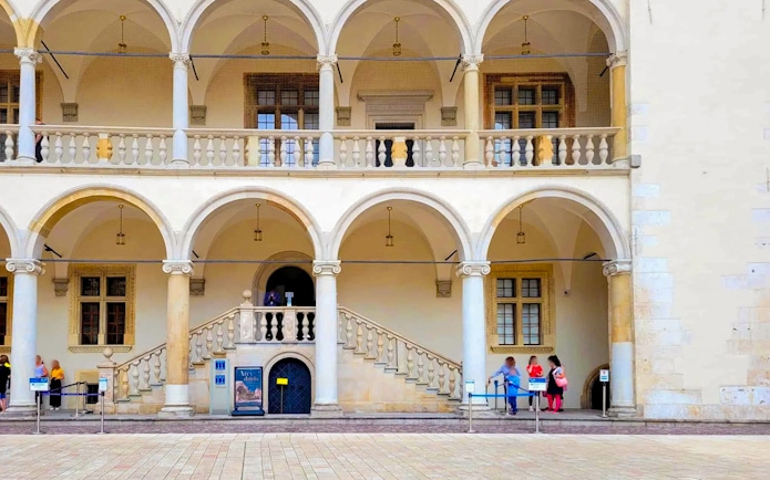 Wawel Castle Royal Apartments entrance with arched balconies and visitors.