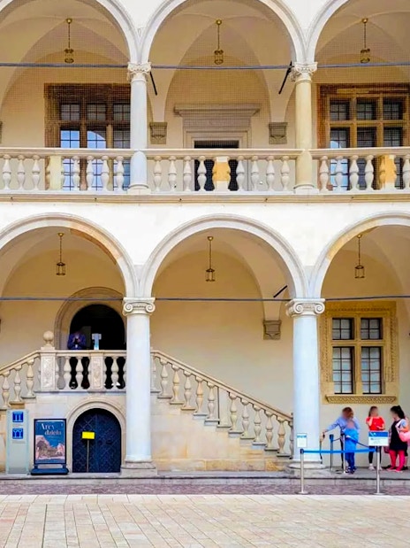 Wawel Castle Royal Apartments entrance with arched balconies and visitors.