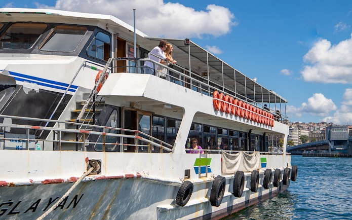 Tourists on a boat enjoying the Istanbul Bosphorus sightseeing cruise with an audio guide.