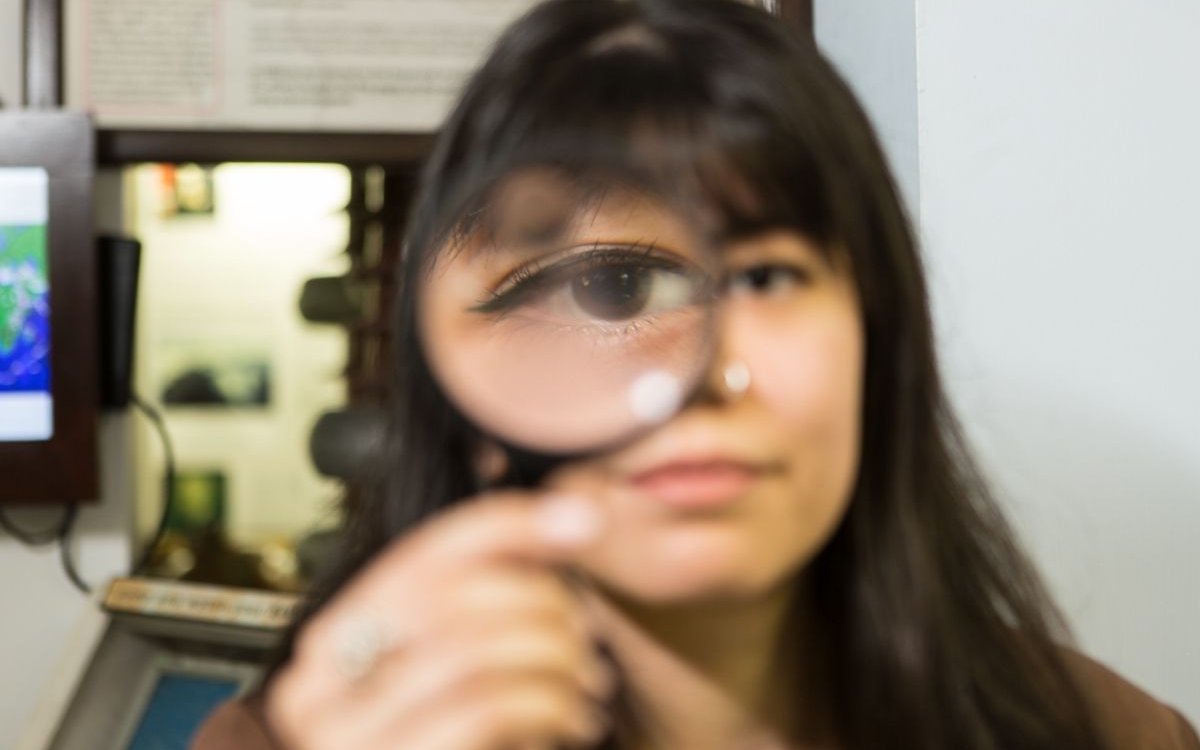 Person holding magnifying glass at National Wax Museum Plus murder mystery event.