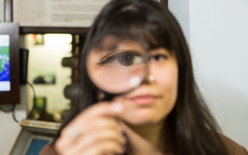 Person holding magnifying glass at National Wax Museum Plus murder mystery event.