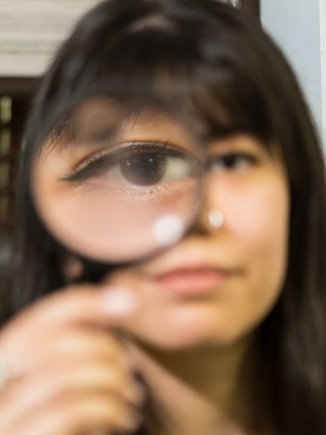 Person holding magnifying glass at National Wax Museum Plus murder mystery event.