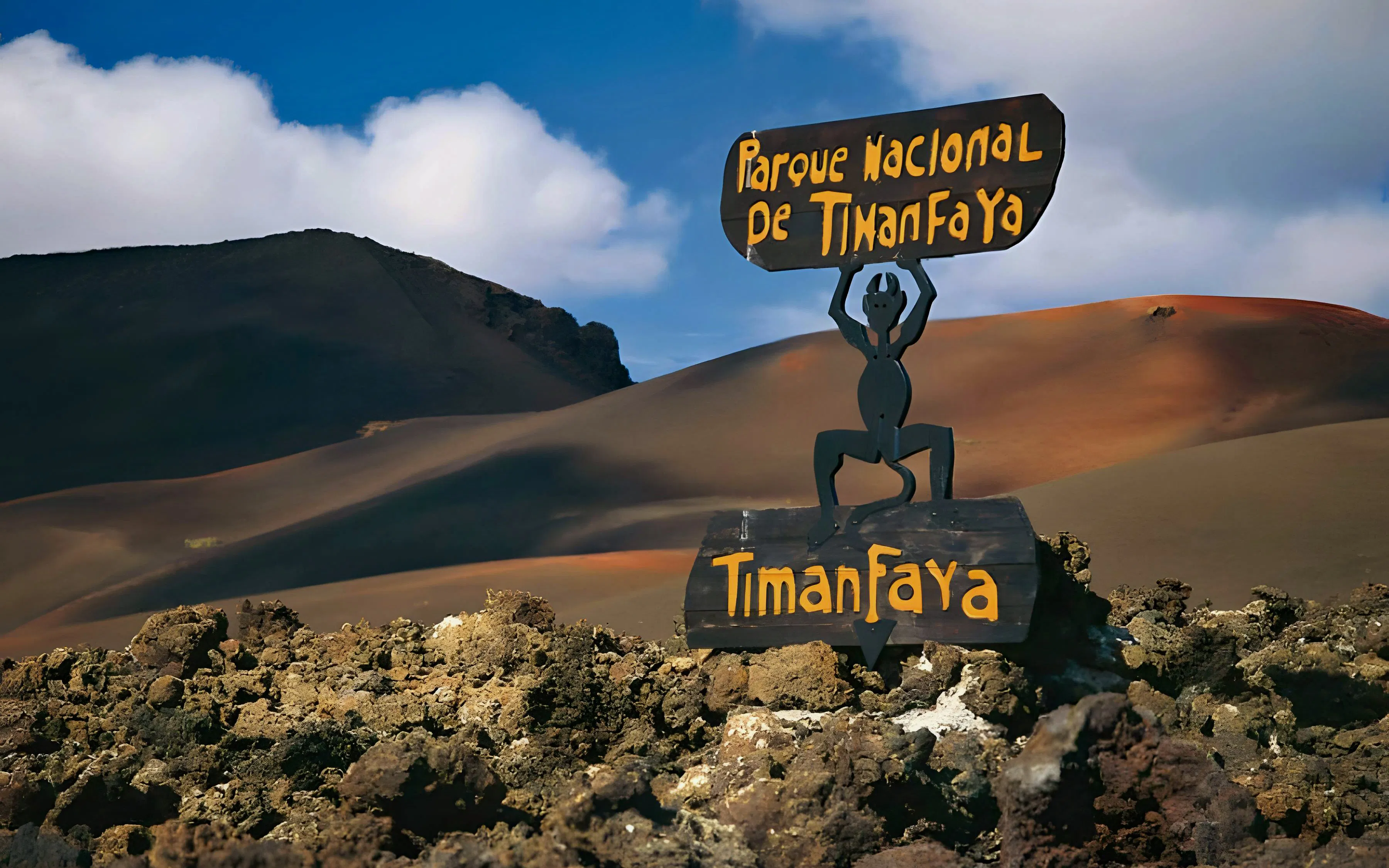 Sign at Timanfaya National Park with volcanic landscape in the background.
