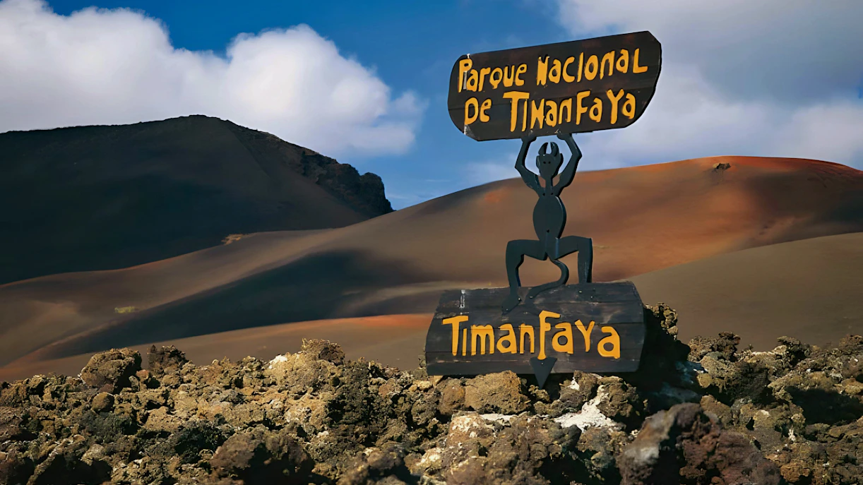 Sign at Timanfaya National Park with volcanic landscape in the background.