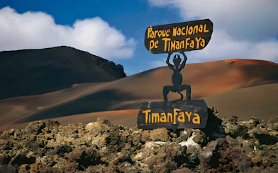 Sign at Timanfaya National Park with volcanic landscape in the background.
