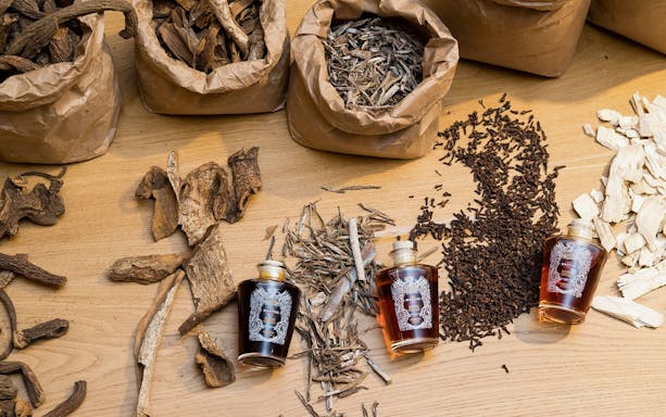 Casa Martini tour showcasing herbs and spices with three bottles of vermouth on a wooden table.