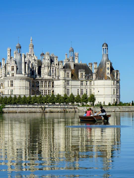 Rowboat on river with view of Château de Chambord, Loire Valley, France.