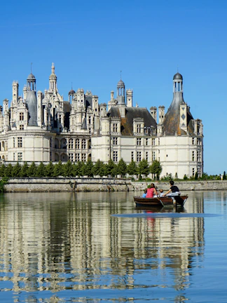 Rowboat on river with view of Château de Chambord, Loire Valley, France.