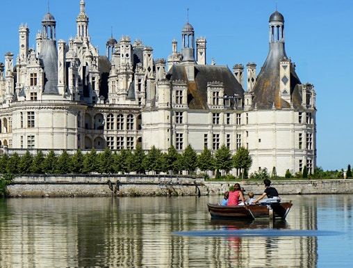 Rowboat on river with view of Château de Chambord, Loire Valley, France.