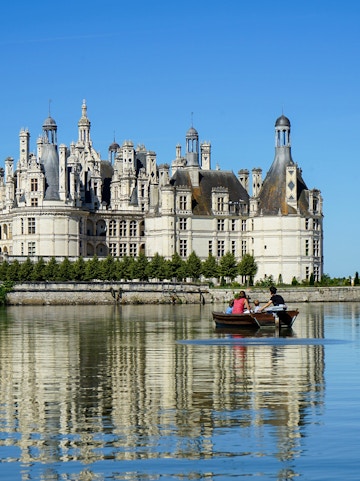 Rowboat on river with view of Château de Chambord, Loire Valley, France.