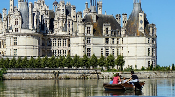 Rowboat on river with view of Château de Chambord, Loire Valley, France.