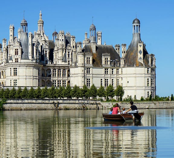 Rowboat on river with view of Château de Chambord, Loire Valley, France.