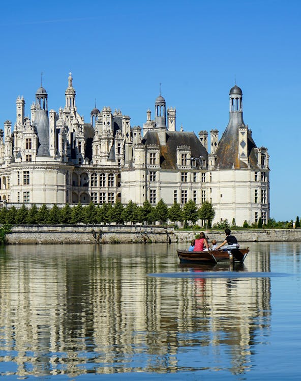 Rowboat on river with view of Château de Chambord, Loire Valley, France.