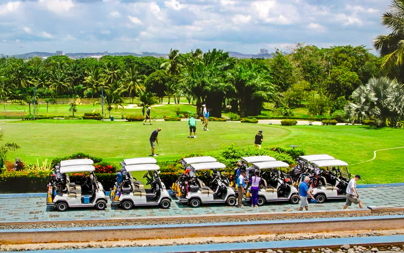 Golfers on the green at Batam Island Country Club with golf carts nearby.