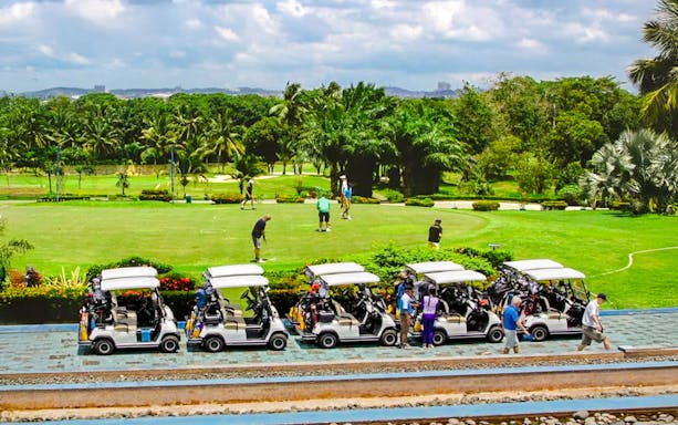 Golfers on the green at Batam Island Country Club with golf carts nearby.