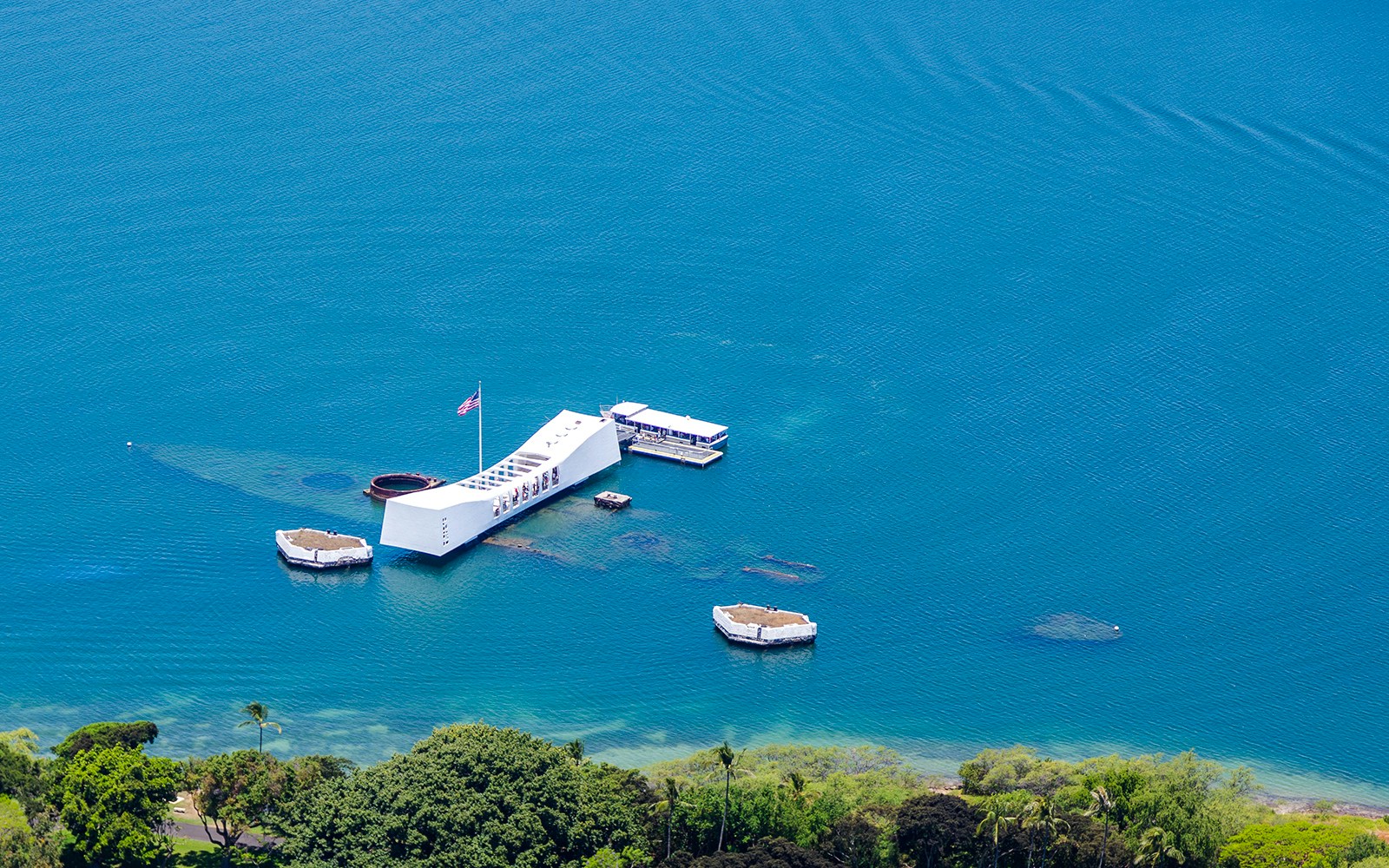 USS Arizona Memorial aerial view in Pearl Harbor, Hawaii, surrounded by blue water.