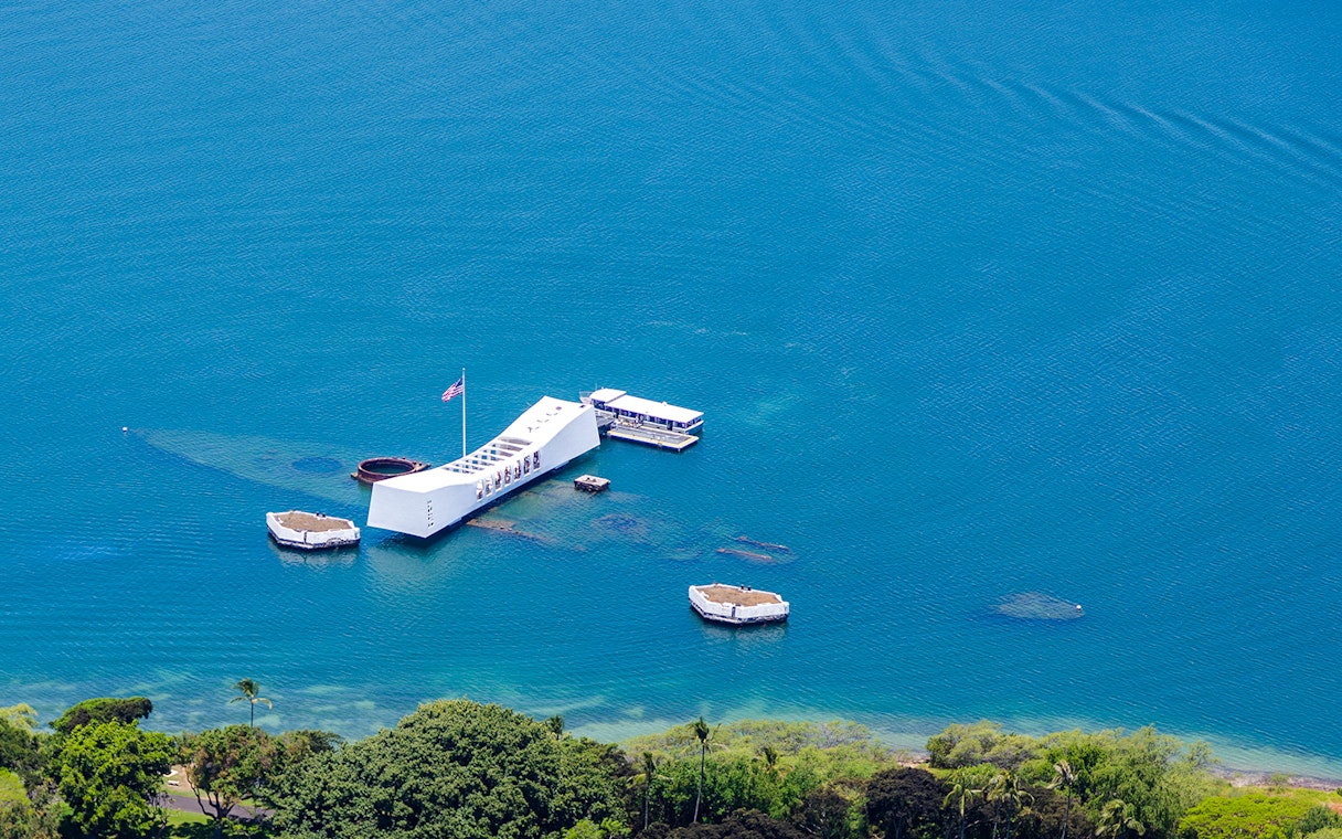USS Arizona Memorial aerial view in Pearl Harbor, Hawaii, surrounded by blue water.