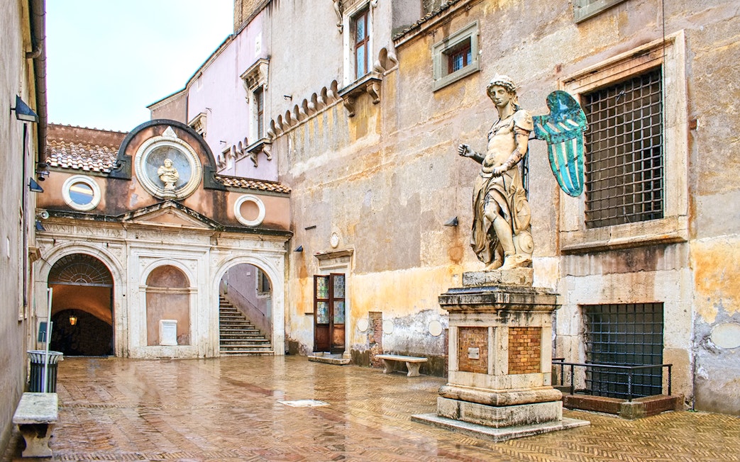 Statue and courtyard at Castel Sant'Angelo, Rome, with reserved entrance access.