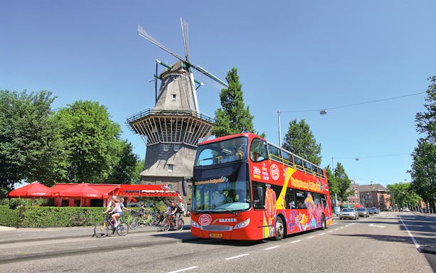 City Sightseeing Amsterdam Hop On Hop Off bus passing a windmill.