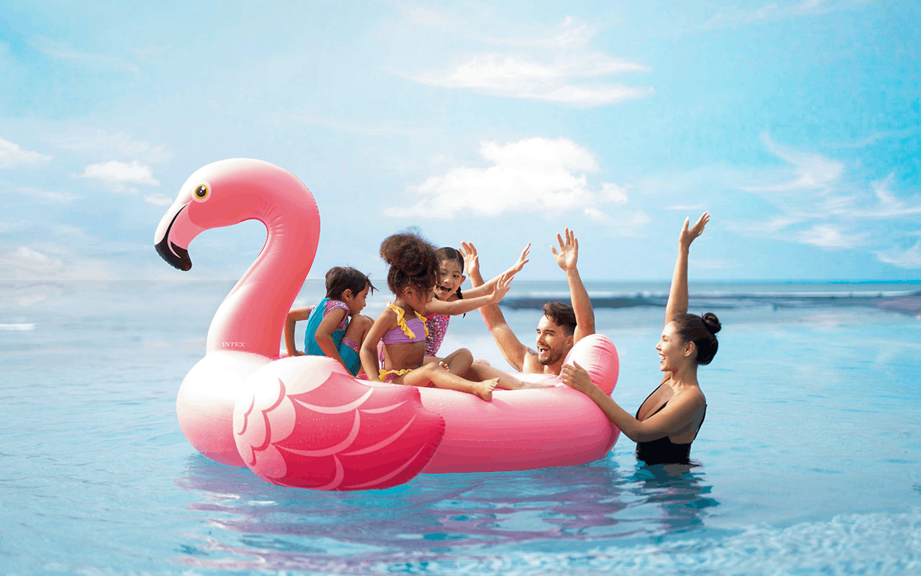 Family enjoying a pink flamingo float at Flamingo Beach Club.