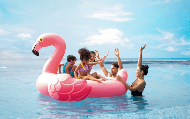Family enjoying a pink flamingo float at Flamingo Beach Club.