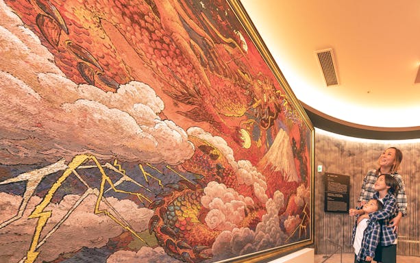 Visitors admiring a vibrant dragon mural at Koji Kinutani Tenku Art Museum.