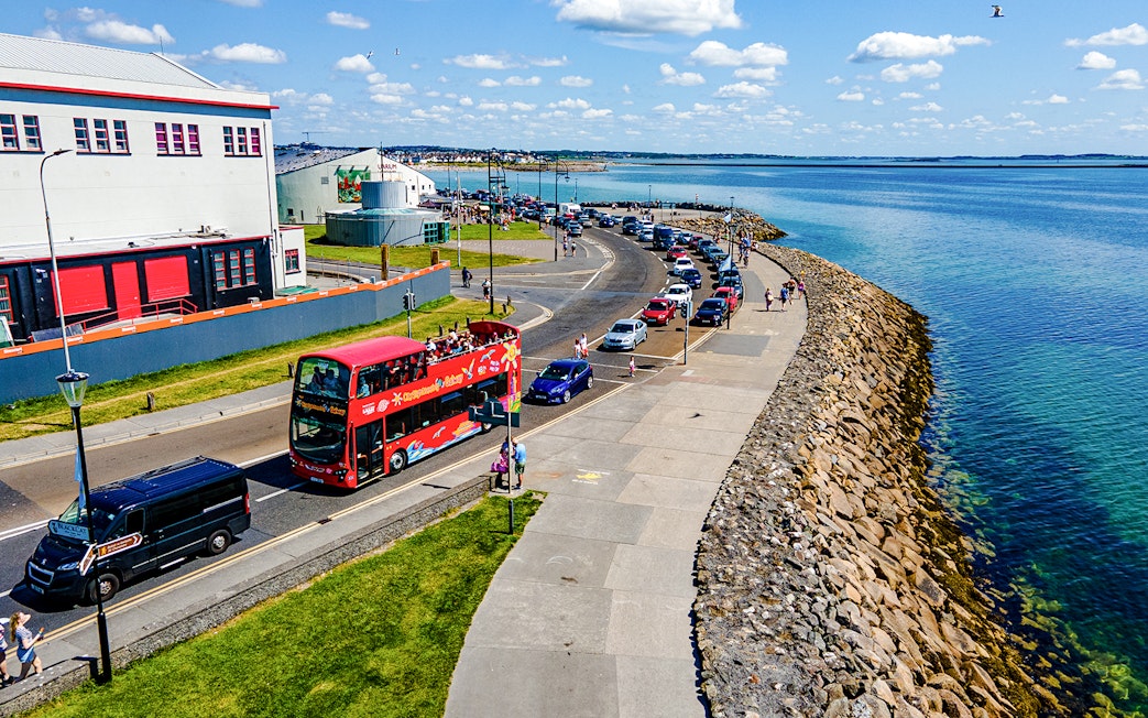 Double-decker bus on Galway Hop-On-Hop-Off Tour passing by the beach.