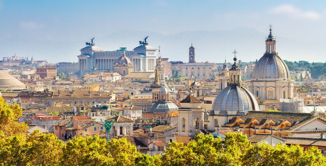 Rome skyline featuring the Colosseum and St. Peter's Basilica at sunset.