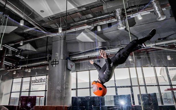 Indoor skydiver in flight with instructor in wind tunnel.