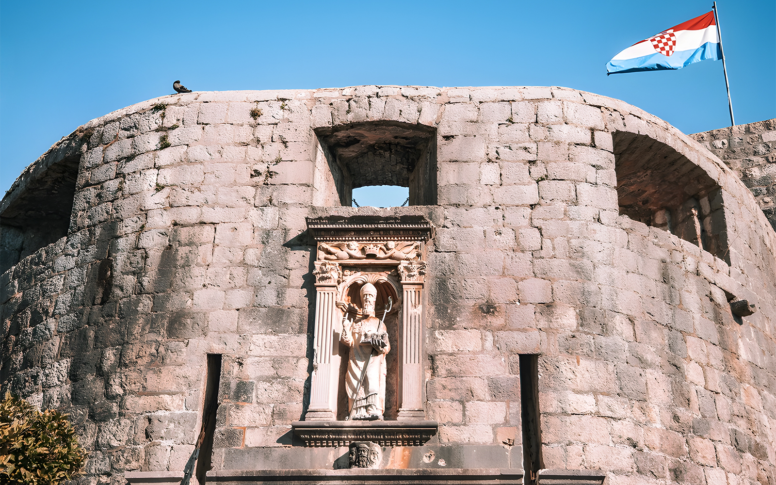 Dubrovnik city wall with statue and Croatian flag, Game of Thrones tour location.