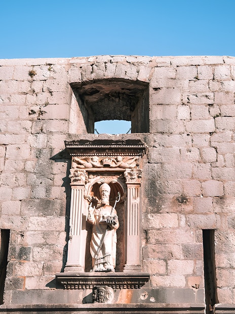 Dubrovnik city wall with statue and Croatian flag, Game of Thrones tour location.