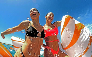 Two people enjoying a swim with inflatable rings on a cruise near Metopi, Agistri, and Aegina Islands.