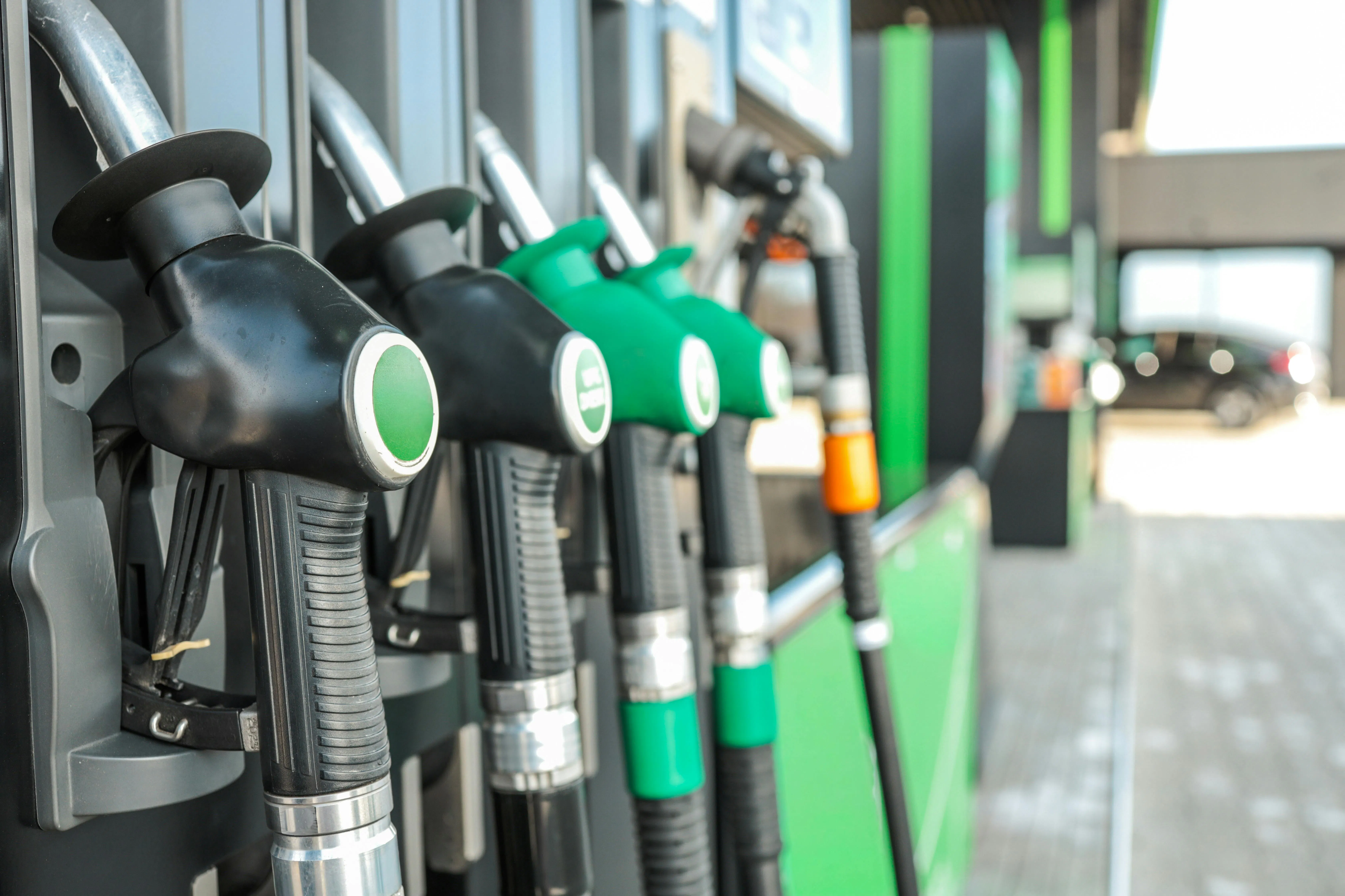 Gasoline pumps at a gas station with a car in the background.
