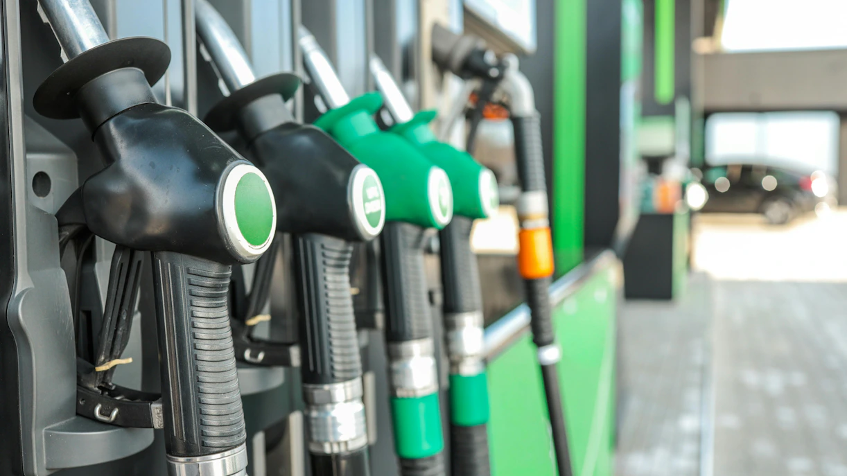 Gasoline pumps at a gas station with a car in the background.